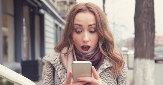woman looking at phone in shock