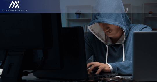man in dark on computer with hood up